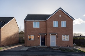 A two-story brick house with a dark roof, a front door, and two windows on the ground floor. - Pottery Wharf Horizon Stays (Stockton-on-Tees)
