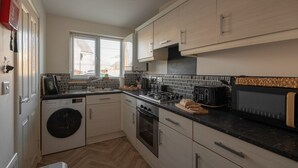 Eine kleine Küche mit Waschmaschine, Backofen und Mikrowelle.