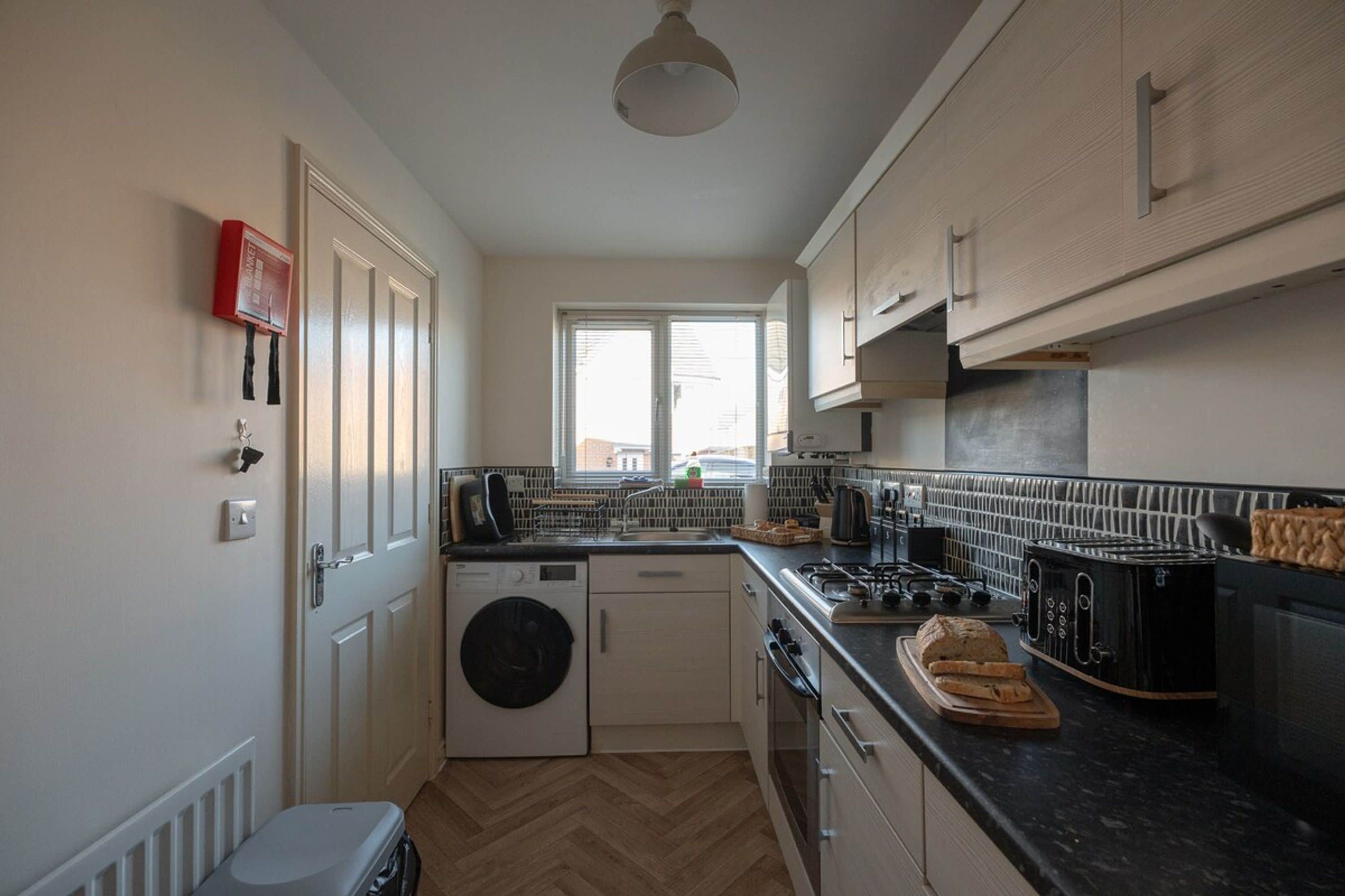A compact kitchen with a washing machine, a stove, and a toaster.