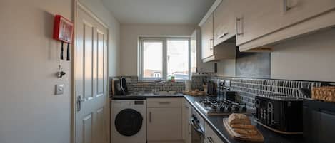 A compact kitchen with a washing machine, a stove, and a toaster.