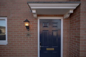 A dark blue door with a brass knocker, a white-framed window, and a brick wall. - Pottery Wharf Horizon Stays (Stockton-on-Tees)