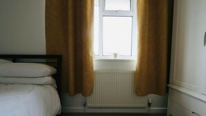 A bedroom with a bed, a window with curtains, a radiator, and a wooden floor. - Thornwood House Horizon Stays (Stockton-on-Tees)