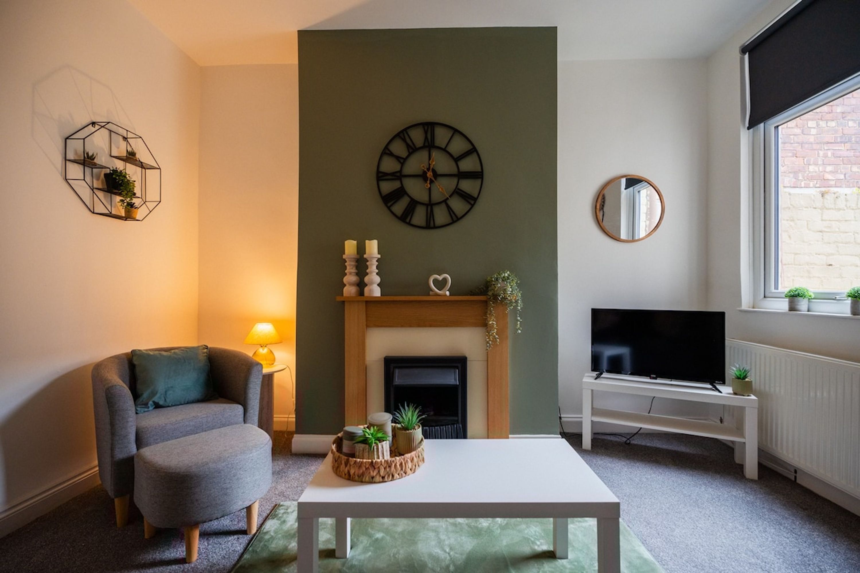 A living room with a sofa, a coffee table, a fireplace, a TV, and a window with a view.