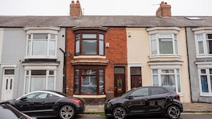 A row of terraced houses with bay windows, a central door, and a visible satellite dish. - The Alfred Suite Redcar (Redcar)