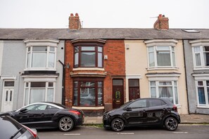 A row of terraced houses with bay windows, a central door, and a visible satellite dish. - The Alfred Suite Redcar (Redcar)