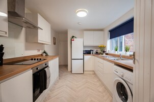 Cocina compacta con estufa, horno, refrigerador y lavadora.