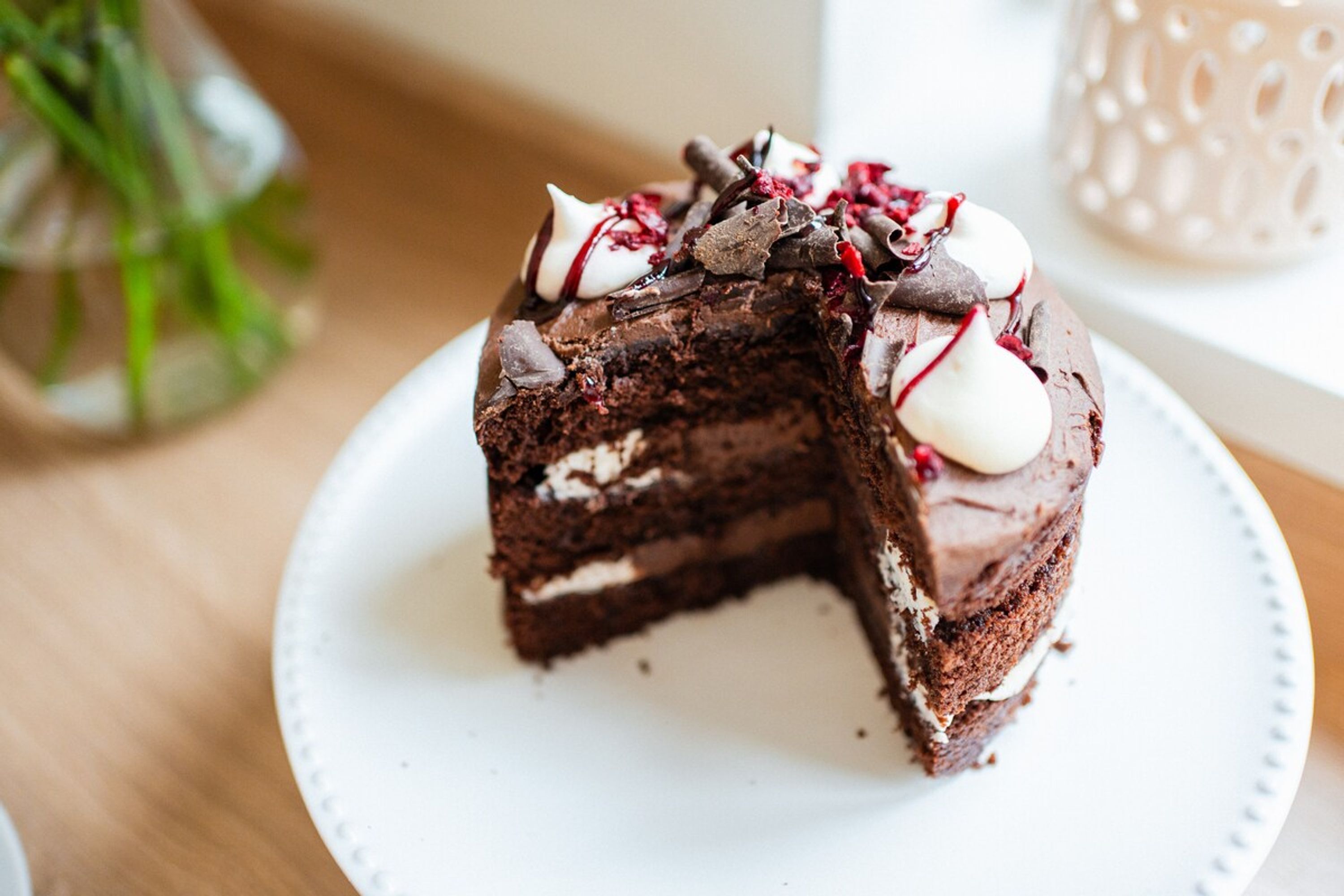 A slice of chocolate cake with cream and berries on a white plate.