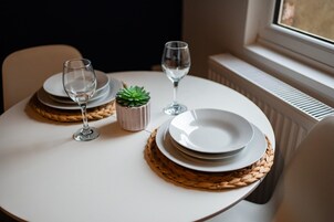 A table set with plates, glasses, and a small plant, with a window and radiator in the background.