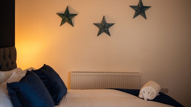 Una habitación de hotel con cama, radiador y tres adornos en forma de estrella.