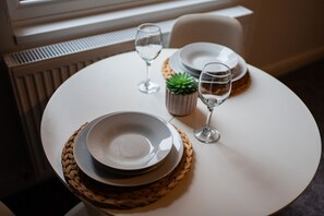 Una mesa dispuesta con platos, vasos y una pequeña planta en maceta, indicando un comedor.