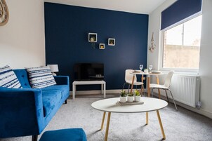 A modern living room with a blue sofa, a white coffee table, and a fireplace.