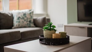 Ein modernes Wohnzimmer mit einer Couch, einem Couchtisch und einer Zimmerpflanze.