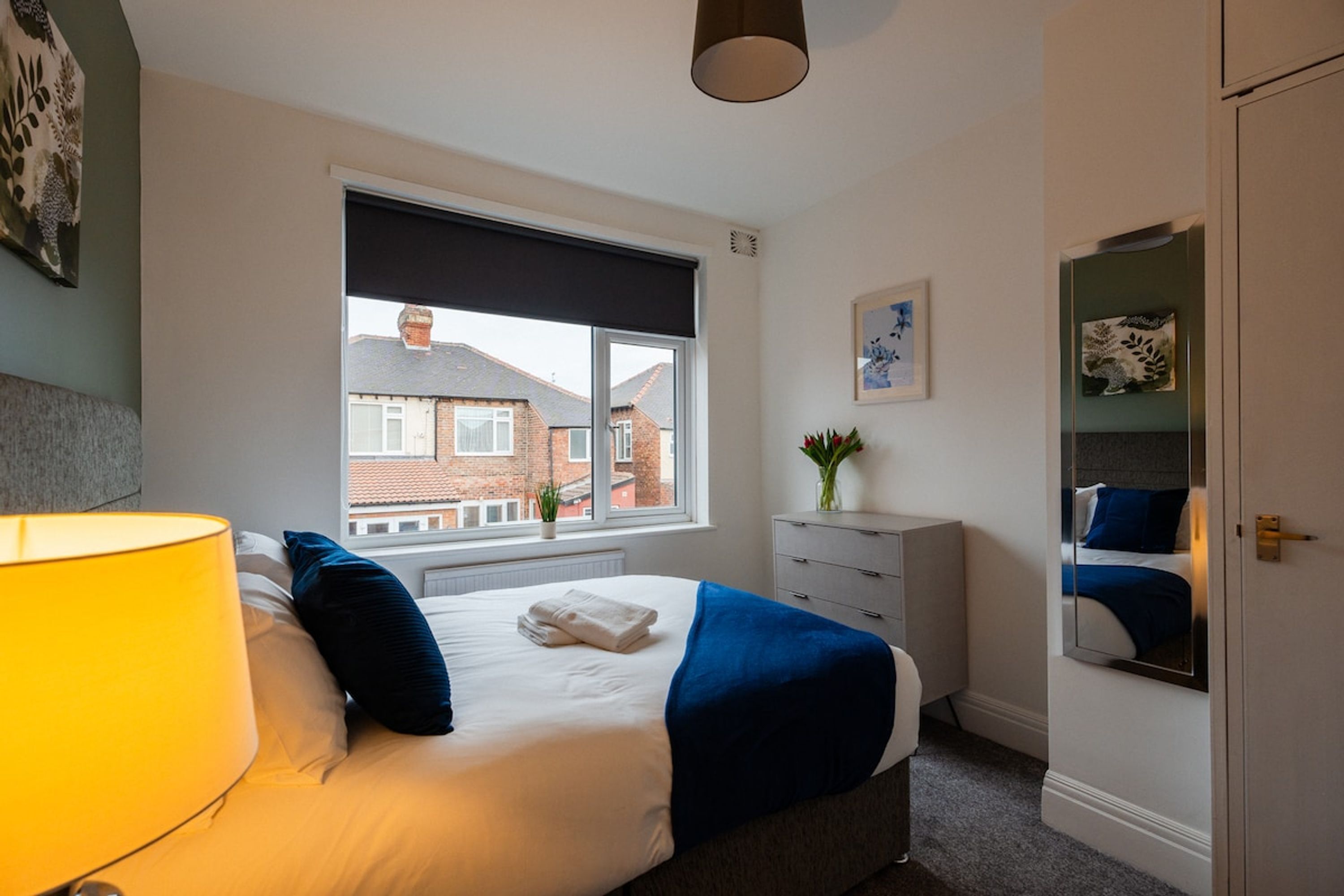 A bedroom with a bed, a window, a dresser, and a mirror.