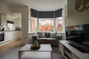 Ein modernes Wohnzimmer mit einer Couch, einem Couchtisch und einem Fernseher.