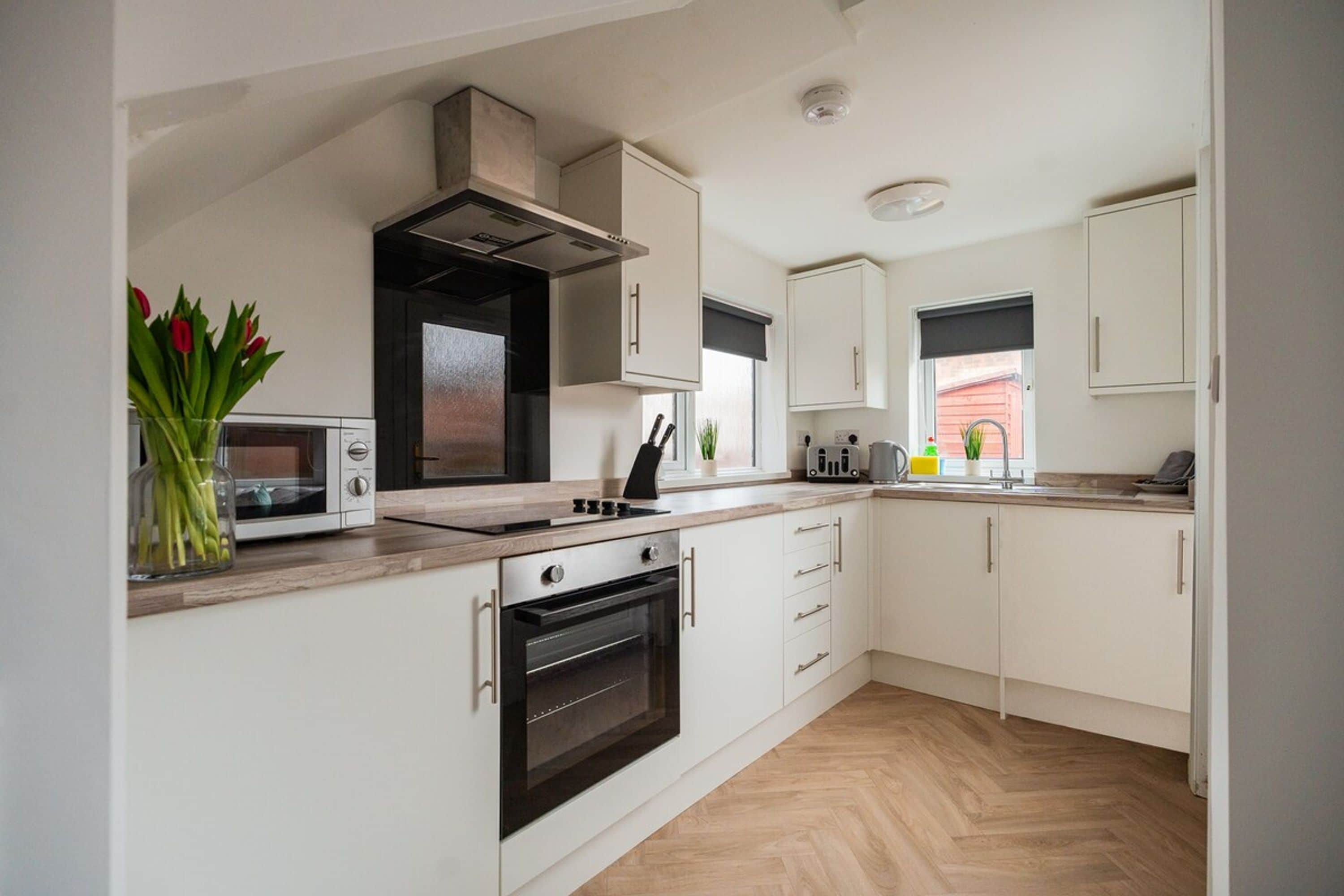 A modern kitchen with white cabinetry, a built-in oven, a microwave, and a gas stove.