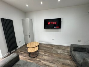 A modern living room with a flat-screen TV mounted on the wall displaying 'NETFLIX'. - 6 Bed Contractor Acom in Hartlepool (Hartlepool)
