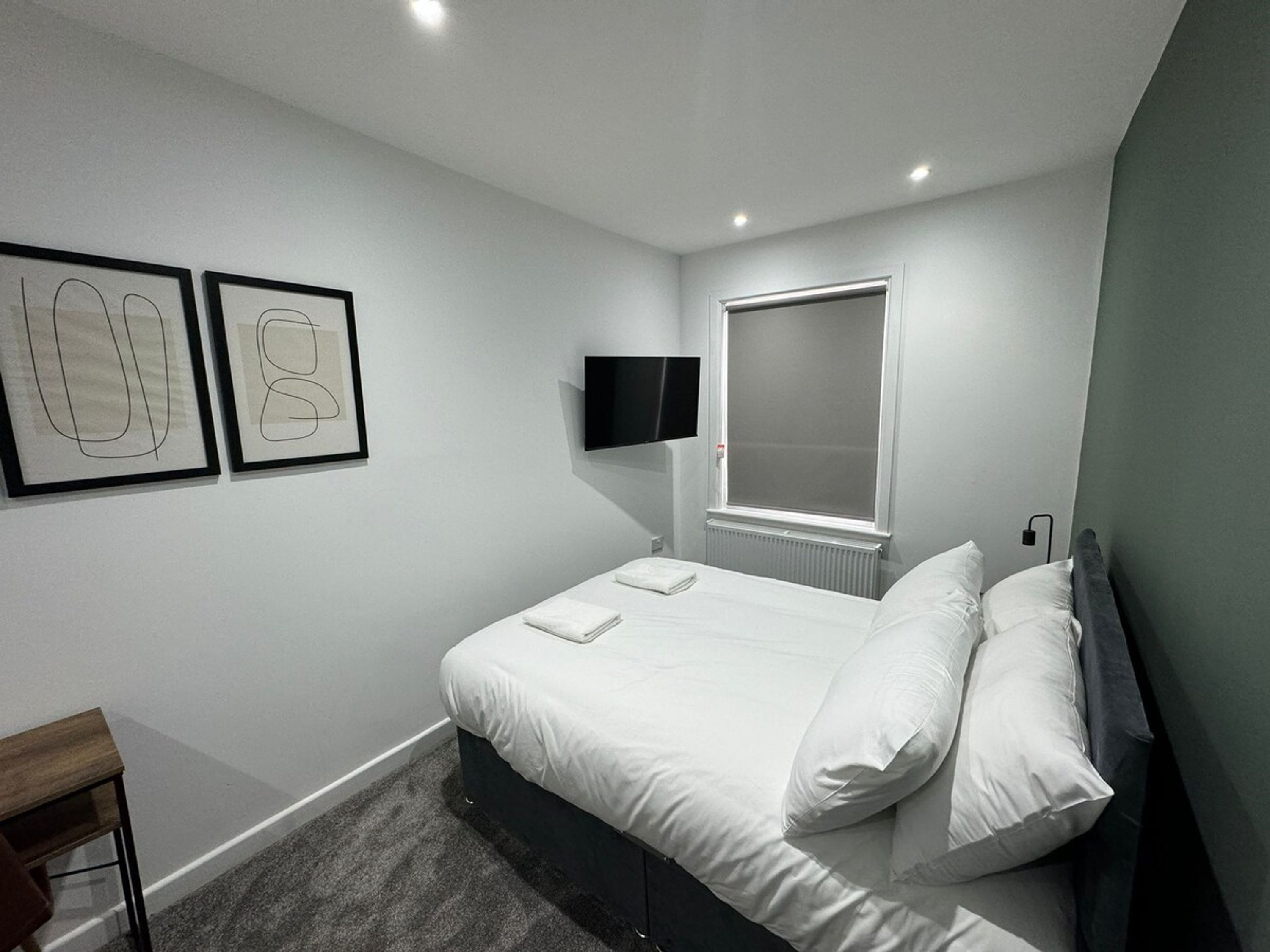 Une chambre  à coucher moderne, équipée d’un lit, d’un téléviseur à écran plat et de deux œuvres d’art encadrées accrochées au mur.