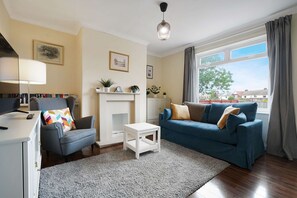 Ein Wohnzimmer mit Kamin, einer Couch, einem Sessel, einem Couchtisch und einem Fernseher.
