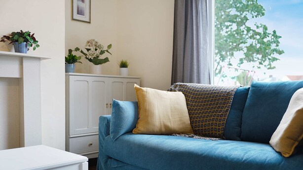 A living room with a blue sofa, a white cabinet, and a small table. - Stunning 3BR Equipped Kitchen By Stay With Us (Chester-le-Street)