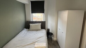 A bedroom with a bed, a window, a wardrobe, and a ceiling light. - Romney House Central Middlesbrough (Middlesbrough)