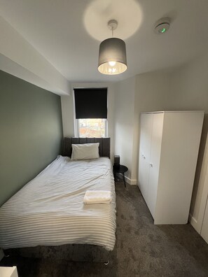Ein Schlafzimmer mit Bett, Fenster, Kleiderschrank und Deckenleuchte.