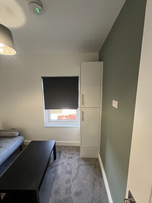 Ein Zimmer mit einem Bett, einem Schreibtisch, einem Kleiderschrank und einem Fenster mit Blick.