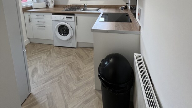A compact kitchen with a washing machine, a sink, and a window with a blind. - Romney House Central Middlesbrough (Middlesbrough)