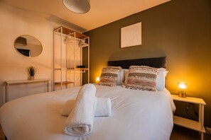 A neatly made bed with rolled towels, a bedside lamp, and a wall-mounted mirror. - The Norton Nook Horizon Stays (Stockton-on-Tees)