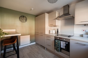 A modern kitchen with a built-in oven, a toaster, and a clock on the wall. - The Norton Nook Horizon Stays (Stockton-on-Tees)