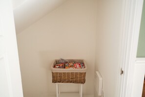 A corner of a room with a white radiator and a wicker basket on a white stand. - The Norton Nook Horizon Stays (Stockton-on-Tees)