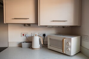 A kitchenette with a microwave, kettle, and a power outlet with a plug. - The Norton Nook Horizon Stays (Stockton-on-Tees)