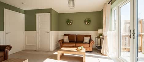 Una sala de estar con un sofá de cuero marrón, una mesa de centro de madera y una puerta blanca.