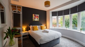 A bedroom with a bed, bedside tables, a wardrobe, a window with a view, and a painting on the wall. - Humber House Thornaby (Stockton-on-Tees)