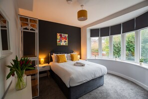 Ein Schlafzimmer mit einem Bett, Nachttischen, einem Kleiderschrank, einem Fenster mit Ausblick und einem Bild an der Wand.