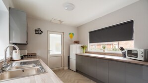 A modern kitchen with a sink, stove, microwave, and a window with a view of the outside. - Humber House Thornaby (Stockton-on-Tees)