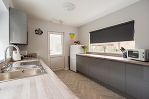 A modern kitchen with a sink, stove, microwave, and a window with a view of the outside.