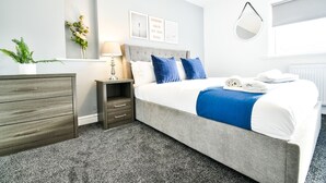 A hotel room with a bed, a nightstand, a dresser, a mirror, and a window. - Dalkeith House Horizon Stays 4 Bed (Hartlepool)