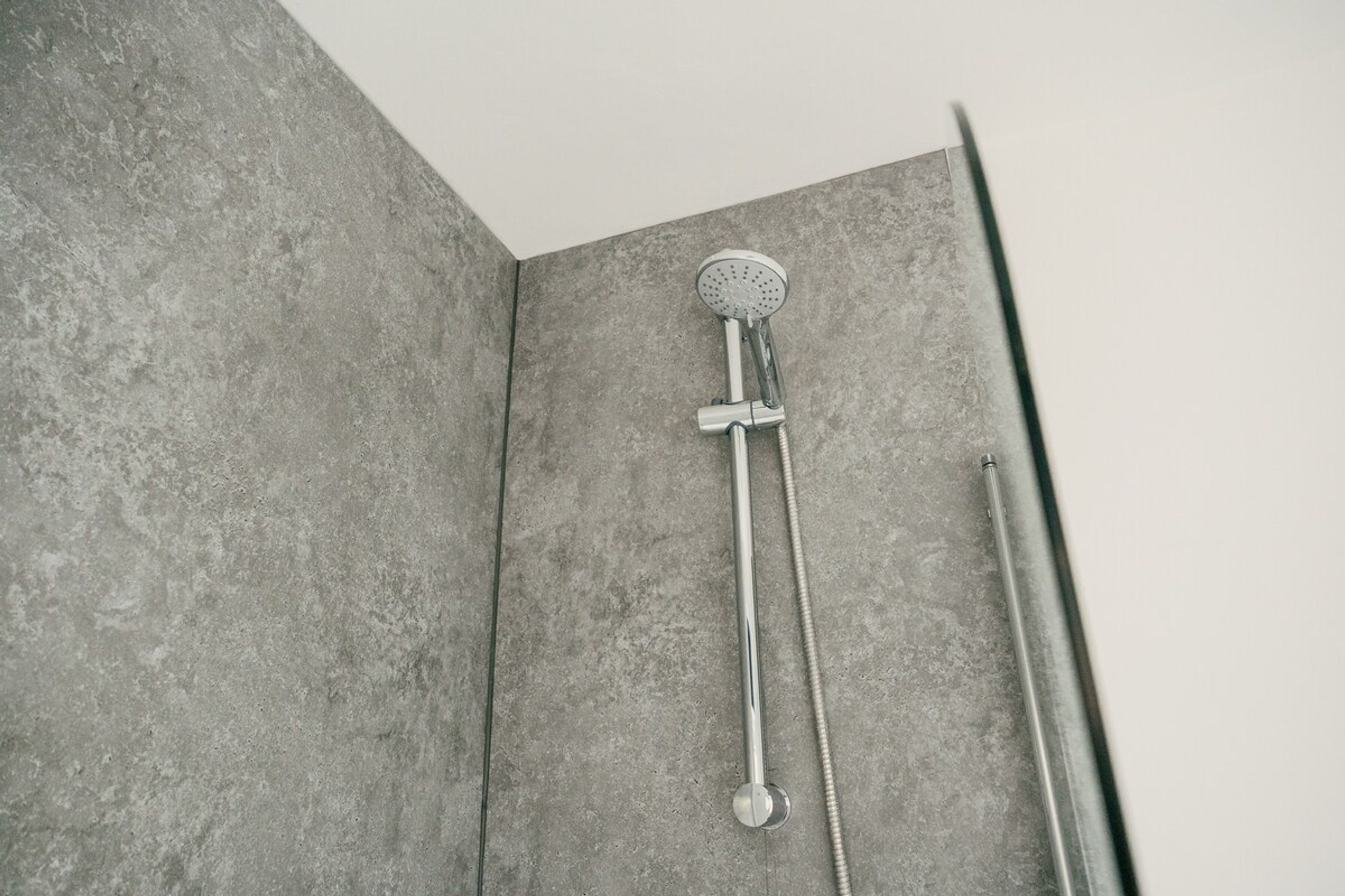A shower with a handheld showerhead and a fixed showerhead, both mounted on a wall.