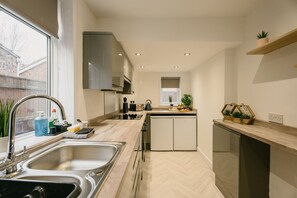Eine moderne Küche mit eingebautem Geschirrspüler, einem Fenster mit Außenblick und einer Arbeitsplatte mit verschiedenen Gegenständen.