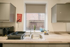 Una cocina moderna con un lavamanos doble, un escurreplatos y un letrero rojo de seguridad contra incendios.