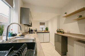 Eine moderne Küche mit Geschirrspüler, Spüle und Wasserkocher, sowie einem Fenster für natürliches Licht.