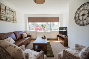 A living room with a brown leather sofa, a wooden coffee table, and a television on a wooden stand. - Winston Bungalow By Horizon Stay (Middlesbrough)