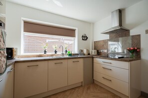 A modern kitchen with a window, built-in cabinets, a stove, and a toaster. - Winston Bungalow By Horizon Stay (Middlesbrough)