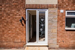 A brick building with a white-framed door and a glass door with a floral design. - Winston Bungalow By Horizon Stay (Middlesbrough)