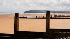 A beach with a wooden fence and a cliff in the background. - Redcar House Horizon Stays (Redcar)
