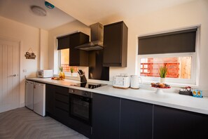 Una cocina moderna con horno integrado, microondas y un ventanal con vistas a un edificio de ladrillo.
