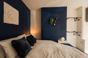 Ein modernes Schlafzimmer mit einem großen Bett, einem Wandbehang, einer geometrischen Wandkunst und einem schlichten Nachttisch.