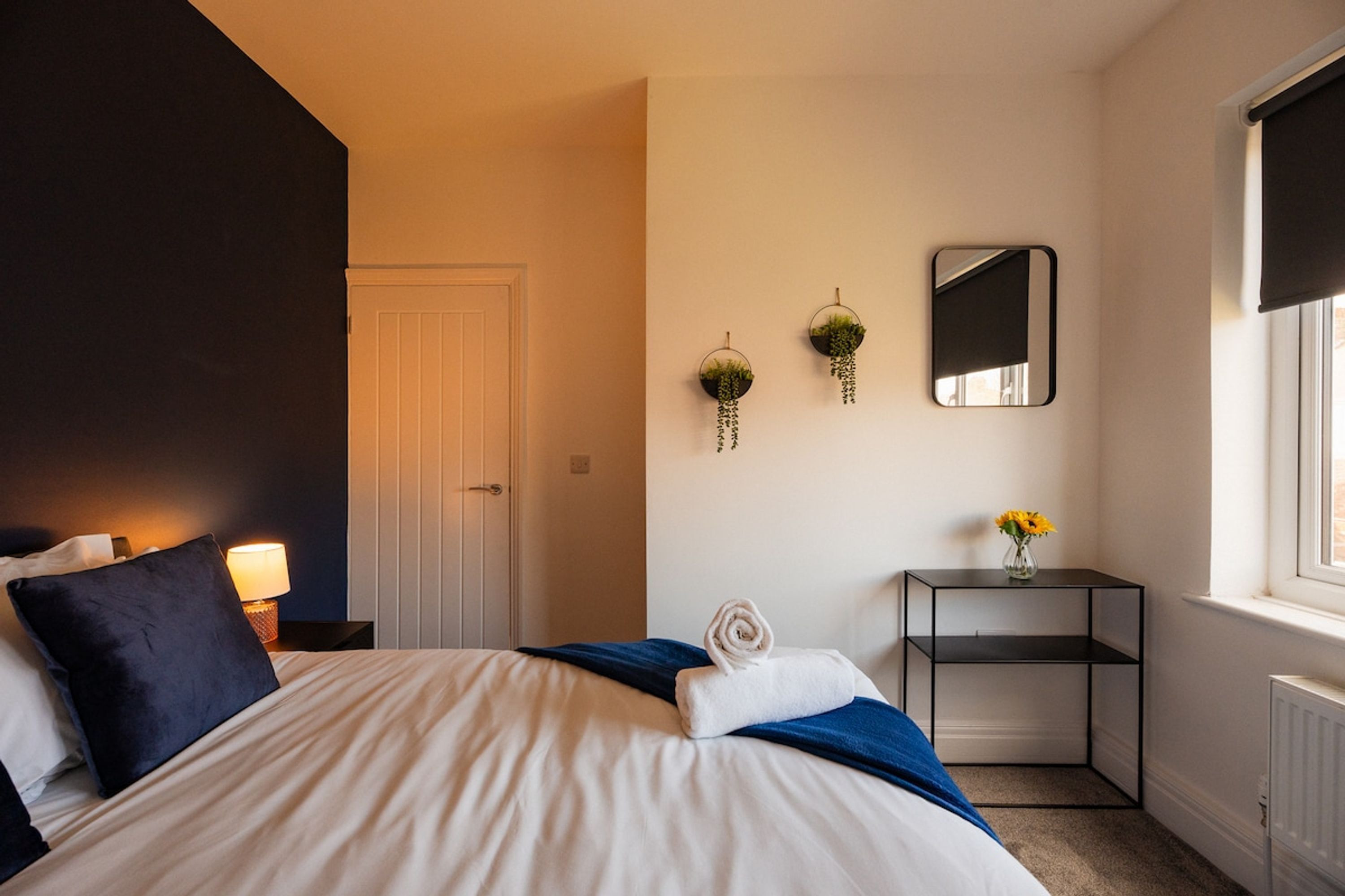 A bedroom with a bed, bedside table, and a window.