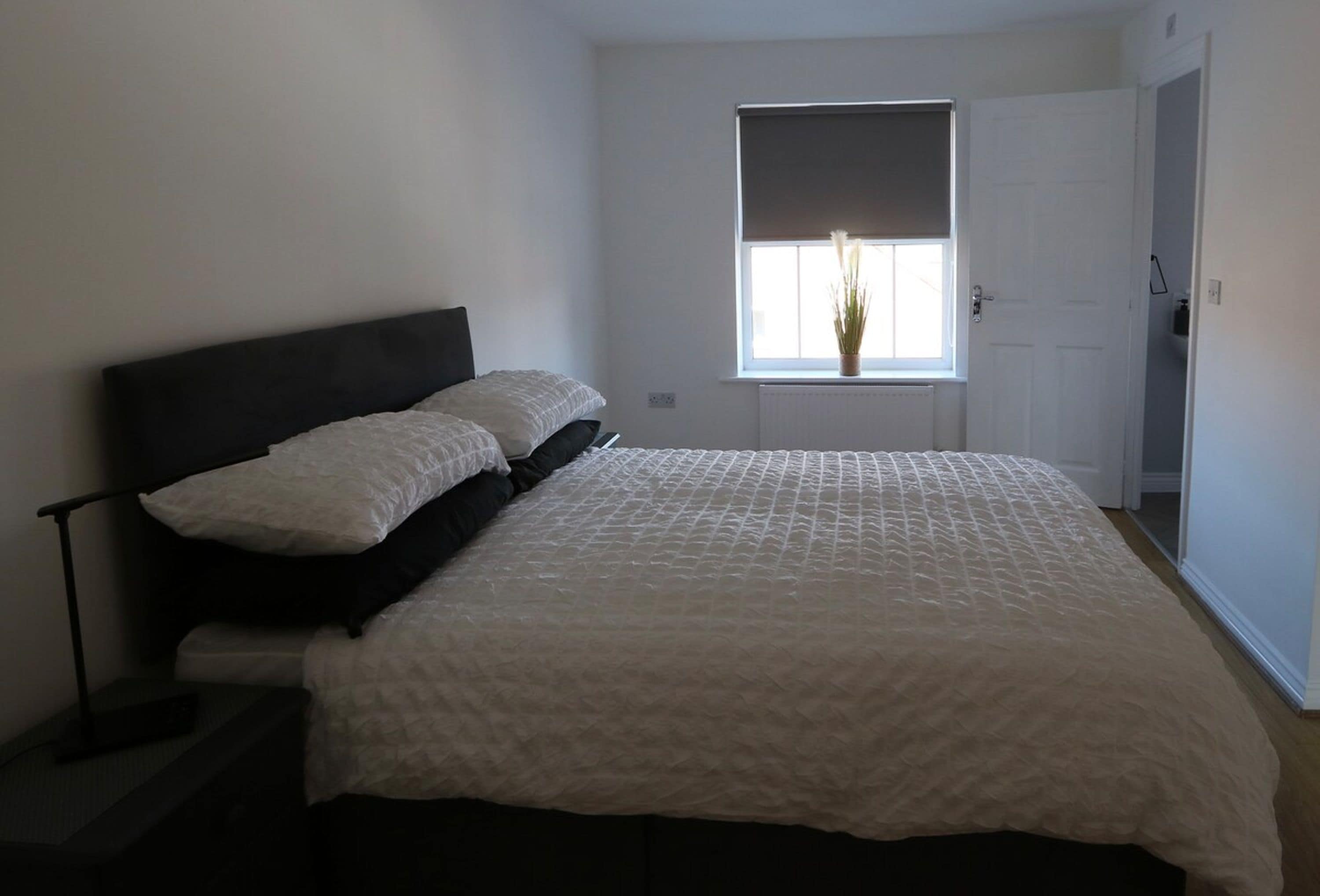 A bedroom with a bed, a window with a view, and a door.