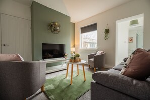 A living room with a flat-screen TV, a sofa, a chair, a small table, and a green rug. - Laburnum House by Horizon Stays (Redcar)
